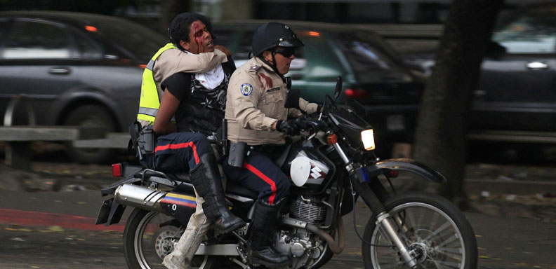 National police transport a detainee after an anti-government protest at Altamira square in Caracas