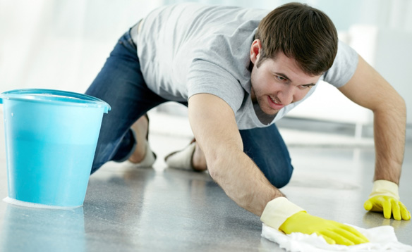 Young man washing floor in protective gloves