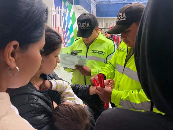 Policías ecuatorianos ubicados en la frontera con Colombia colocan este sábado 25 de agosto de 2018, brazaletes rojos a los migrantes venezolanos que considera vulnerables, como mujeres con niños y embarazadas, para darles prioridad al momento de ser trasladados en autobuses a la zona fronteriza con Perú, en Tulcán (Ecuador)/ Foto: EFE